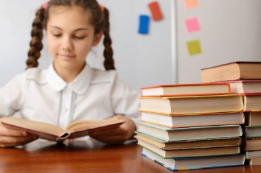 Arka planda okuyan bir kız olan bir yığın kitabın resmini kapat. Ödev yapmak, edebiyat okumak.