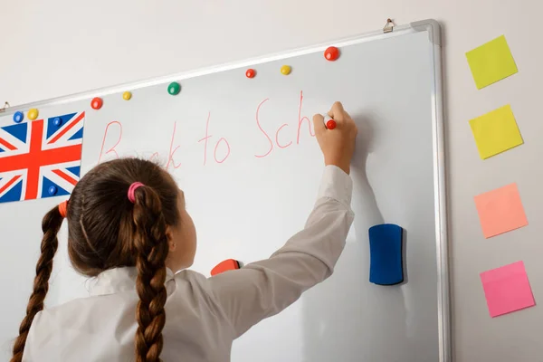 可爱的小女孩在黑板上写着 回学校 的题词 — 图库照片