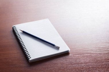 Defter ve mavi kalem ahşap masada.