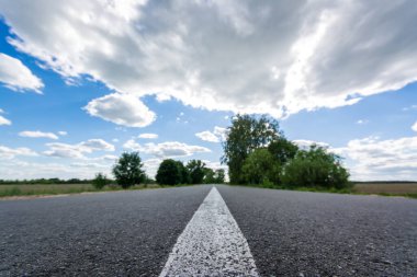 Yeni asfalt yol yazın yapıldı. Otoyolun güzel manzarası, ağaçlar ve bulutlu güzel kontrast gökyüzü.