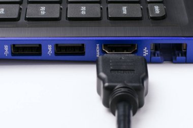 Modern mavi dizüstü bilgisayarın HDMI portu yakınındaki beyaz arka planda HDMI kablosu. Yatay çekim
