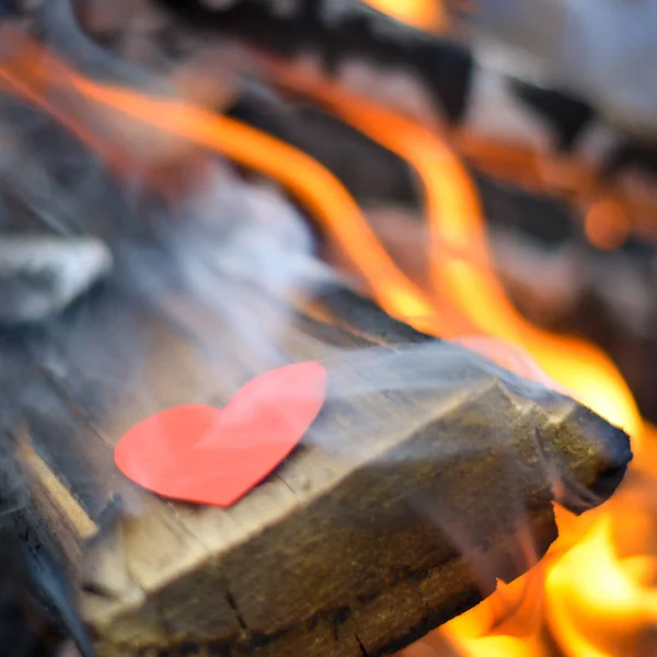 Red paper heart burns in the fire. concept of broken relationship, unrequited love, broken heart