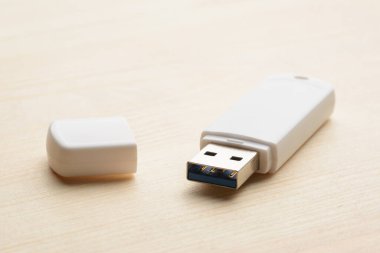 Beyaz fişi çekilmiş USB çubuğu ve hafif ahşap bir masa.
