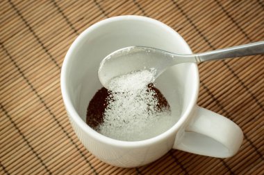 Kahveyle fincana biraz şeker döküyorum. Kahveye şeker ekliyorum. Evde kahve yapıyorum.