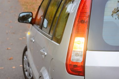 Modern gri hatchback arabası dönüş lambalarıyla kırsal kesimde yola koyuluyor.