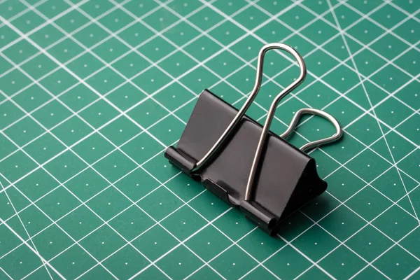 Paper clip on green cutting mat