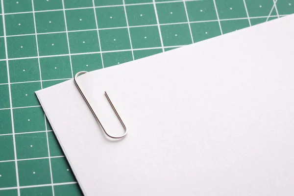 Paper clip with a paper on green cutting mat