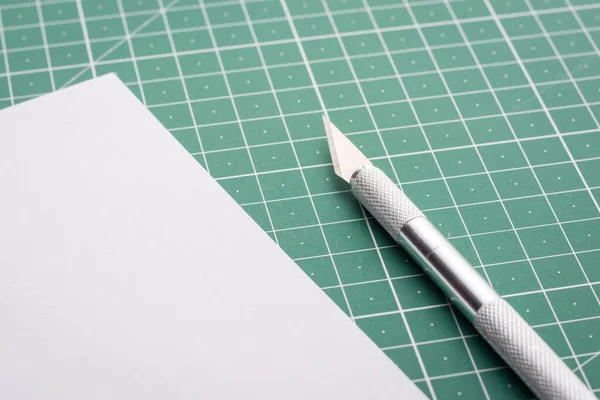 切割垫子时靠近空白白纸的专业刀片 — 图库照片