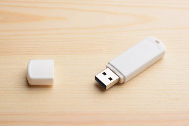 Tahta masasında kapağı olan beyaz USB çubuğu