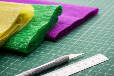 Neşter ve cetvel, hasırın kesilmesi üzerine sanat çalışması için yuvarlak kağıtların yanında.