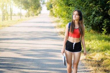 Genç ve güzel bir kız kırsalda bir haritayla yürüyor müzik dinliyor ve doğanın güzelliğine hayran.