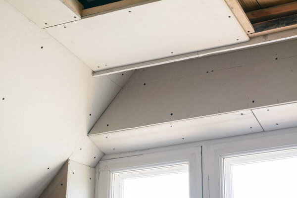 Making suspended ceiling using wooden frame and drywall in a private house. Preparing place for LED lighting on the ceiling near the window