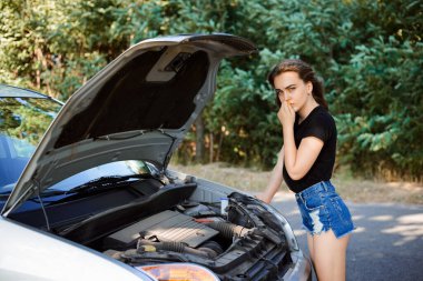 Hüsrana uğramış kız yolda arabası bozulduktan sonra yardım bekliyor.