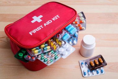 Full-equipped first aid kit with pills and other medicine lays on wooden table. Concept of health care