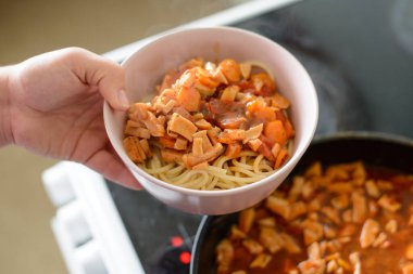 Ev hanımı tüm aile için lezzetli yemekler pişirir. Tabakta sosisli makarna.