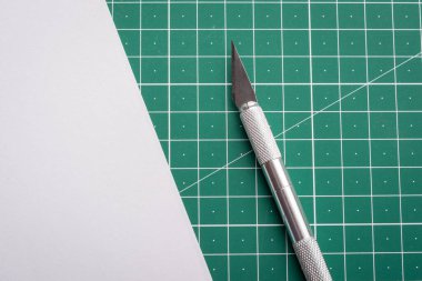 Kesme hasırlı bir masanın üzerindeki beyaz kağıdın yanında neşter. Kesmeden önce
