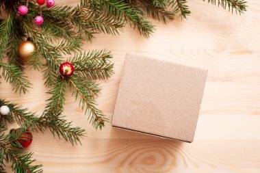 Tahta masadaki paketsiz kutu, kopyalama alanı. Resmin köşesindeki noel ağacı dalları, dekorasyon, üst manzara, düz yatış.