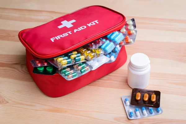 First aid kit with colorful capsules and pills on table. Remedy for diseases, healthcare, emergency.