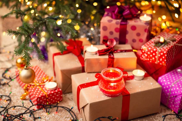 Different presents and some candles under the Christmas tree. Christmas mood