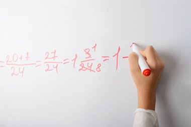 Matematik denklemini beyaz tahtada sayan bir kızın eli. Okul eğitimi, matematik dersi.