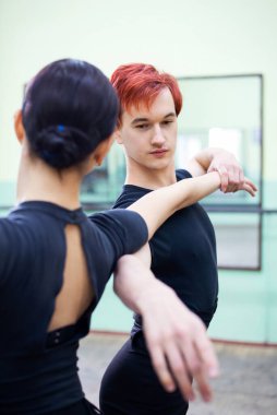 Genç adam stüdyoda siyah elbiseli güzel bir kadınla klasik bale yapıyor. Şehvetli dans, profesyonel bale.