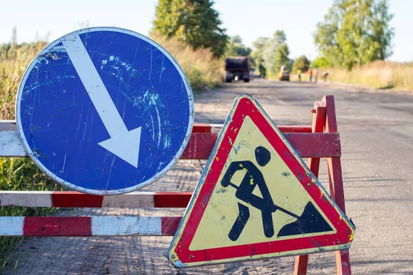 Old road repairing sign on the roadside. Concept of repairing bad roads