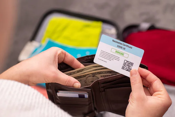 Traveller taking vaccination certificate to her wallet before setting on to a trip. Vaccination passport