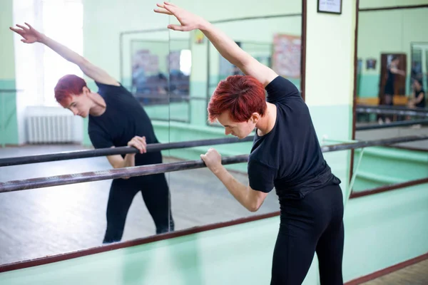 Kızıl saçlı balerin büyük aynanın önünde prova yapıyor. Spor anlayışı, formda kalmak, esneklik, eğitim.