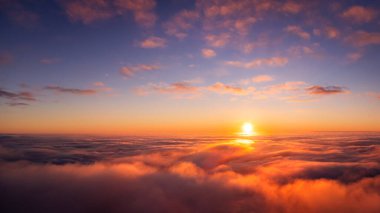 Spectacular aerial photo of setting sun above the clouds. Flying on plane in the evening and witnessing dramatic view of sun going under horizon
