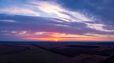 Drone photo of agricultural fields with setting sun in the background. Bright vibrant evening with golden sun going under the horizon