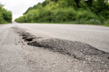 Big humps on asphalt road due to driving overloaded trucks on it. Damaged road in the countryside