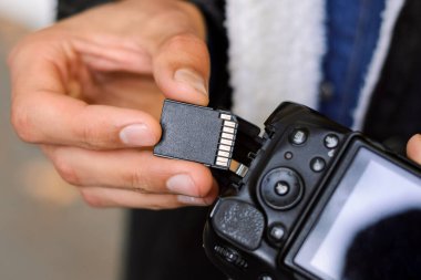 Male photographer putting a flash card into the camera. Technology, professional shooting, close up, details.