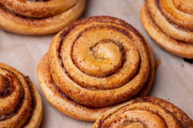 Many fresh baked buns with cinnamon on baking paper. Cooking tasty bakery at home