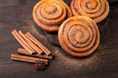 Close-up shot of tasty cinnamon buns on wooden table. Spicy cinnamon rolls on the cutting board