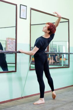 Male ballet dancer training near the mirror in the studio. Elegant dancer learning new elements of the performance, improwing his skills
