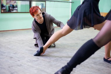 Lesson of choreography with an instructor. Male teacher helps young dancer to perform certain element correctly