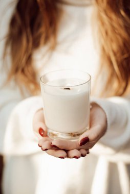Close-up shot of a girl holding white burning candle. Aromatherapy with a candle