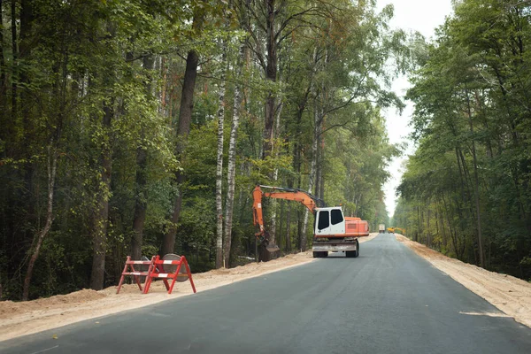 stock image Excavator making safe roadside for new constructed road. Repairing old road