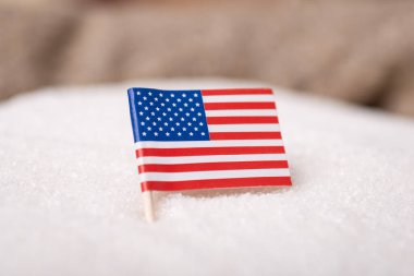 Close-up shot of flag of USA in granulated sugar. Production of white sugar from sugar beets in the US concept