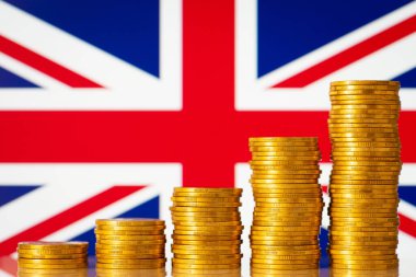 Stacks of gold coins in front of Great Britain flag. Financial development of Great Britain