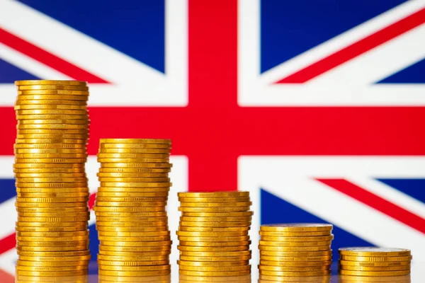 Golden coins in front of Great Britain flag. Concept of economic recession of Great Britain