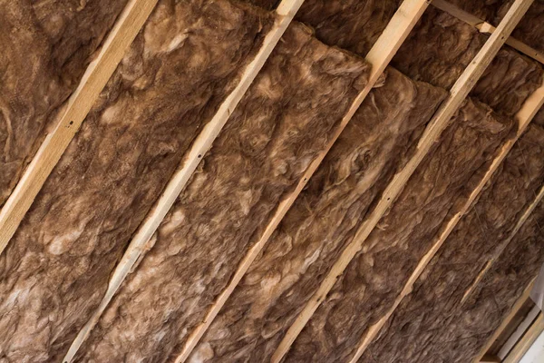 プライベートハウス内の木製の天井近くの傾斜壁に木製のフレームに茶色のガラスウール グラスファイバーで家を暖める — ストック写真