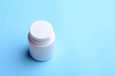 Kapalı beyaz plastik bir şişe ve masada haplar duruyor. Tıp kavramı