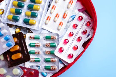 Mavi masanın üzerinde farklı haplar olan ilk yardım çantası.