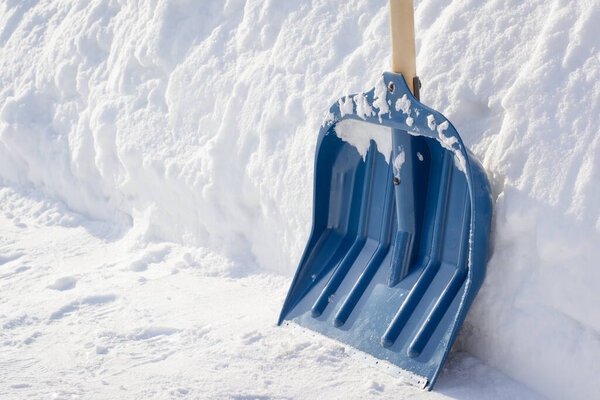 Snow shovel with a wooden handle after cleaning sidewalk in the street