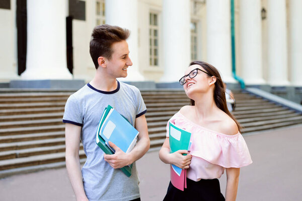 Молодые студенты проводят время вместе. Чтение книги, общение, стоя рядом с лестницей старого традиционного университета в маленьком городке