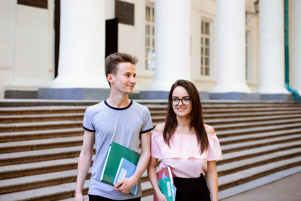 Два счастливых друга возвращаются домой после занятий. Улыбающиеся студенты счастливы вернуться в зал проживания после напряженного рабочего дня, веселятся вместе и общаются по дороге домой