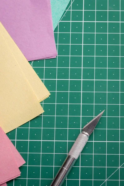 Cutting papers of different colour on a green cutting mat