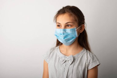 Tıbbi maske ve eldiven takmış küçük bir kızın stüdyo portresi. Covid-19 salgını kavramı