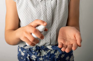 Kendini tehlikeli virüslerden ve mikroplardan korumak için antibakteriyel el el dezenfektanı kullanan bir kız.